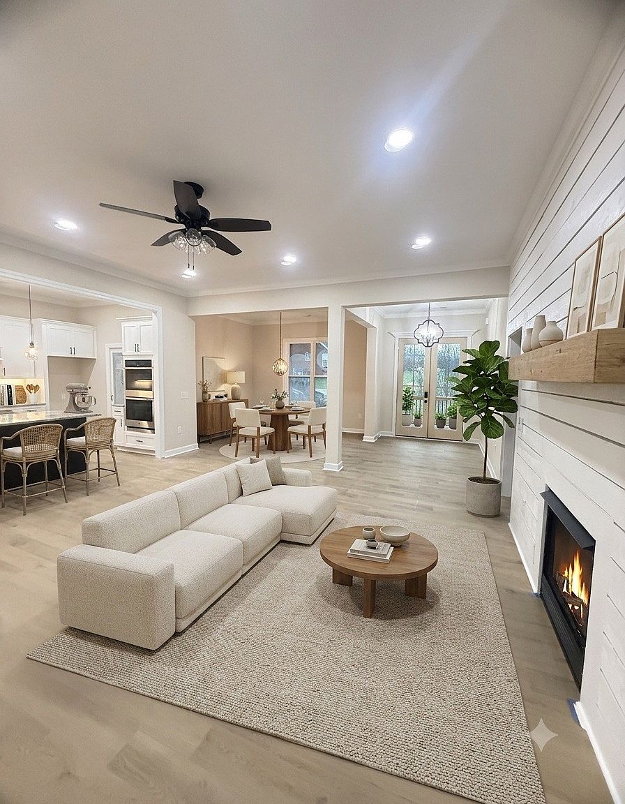 Bright open living room with a white sectional sofa, round wood coffee table, and fireplace.