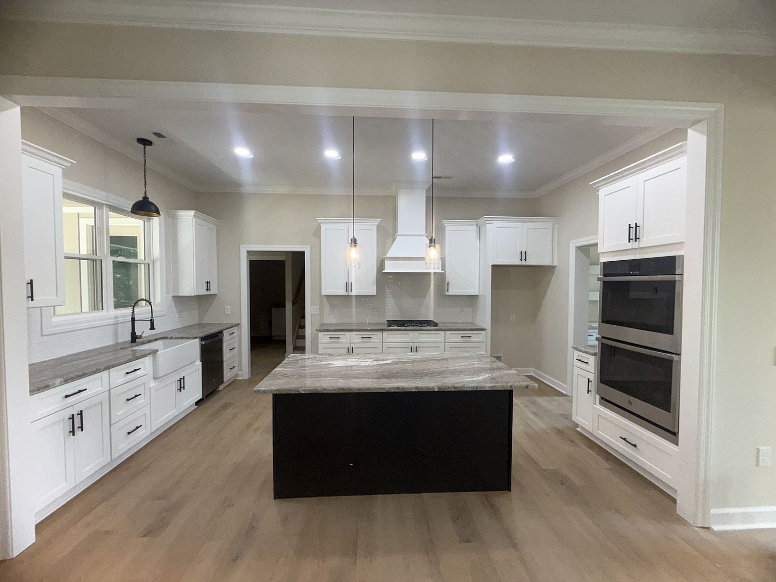 Bright modern kitchen with white cabinetry, marble countertops, and a large central island with a dark base.