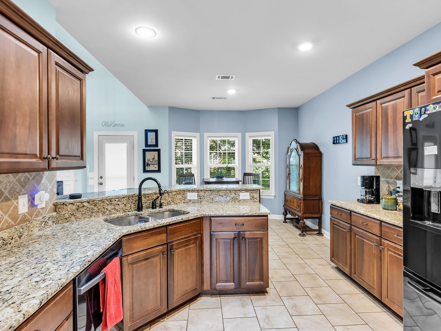 110 Bancroft Ct photo 12 Kitchen with granite countertops, central island, and dark wood cabinets; blue walls and a bay window dining nook.
