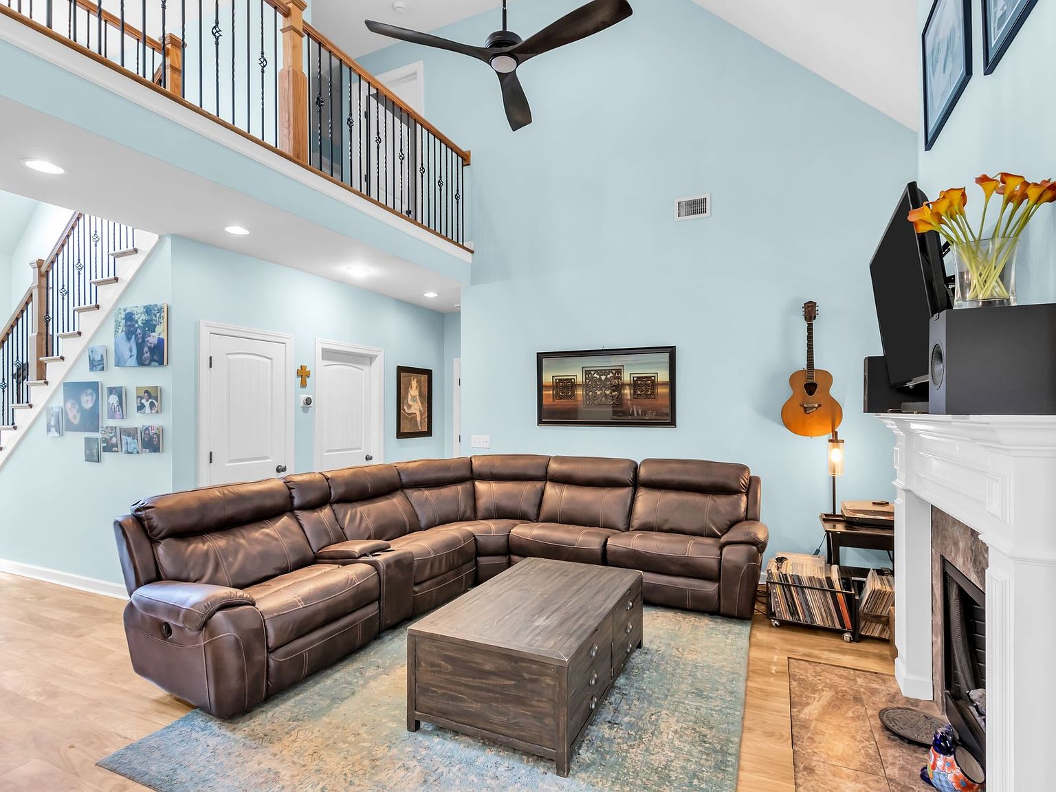 110 Bancroft Ct photo 16 Bright living room with a large brown leather sectional, a wooden coffee table, and a blue area rug.