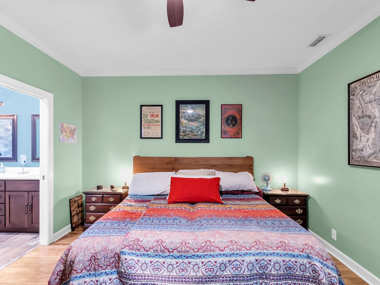 110 Bancroft Ct photo 20 Green-walled bedroom with a wooden-bed frame, colorful patterned quilt, and a red decorative pillow between white pillows.