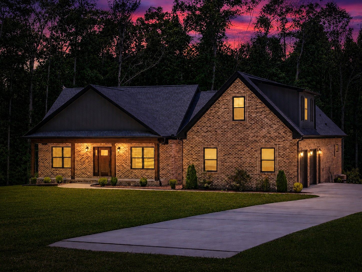 Brick suburban home at dusk with illuminated windows and a warmly lit front porch, set against a dark tree line and purple sunset sky.